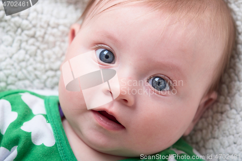 Image of cute little baby playing with hands and smiling