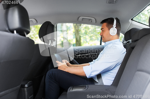 Image of passenger with headphones using tablet pc in car