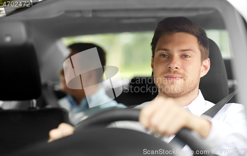 Image of male taxi driver driving car with passenger