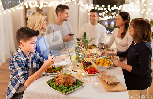 Image of boy with smartphone at family dinner party