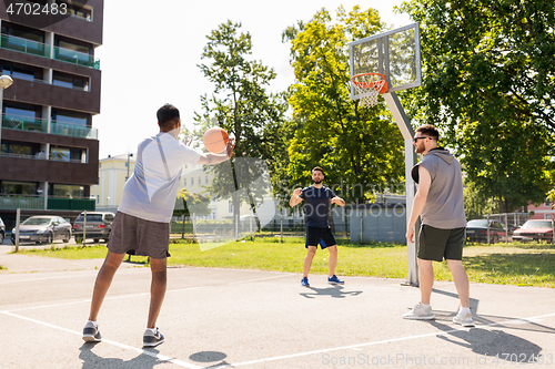 Image of group of male friends playing street basketball