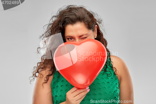 Image of playful woman holding red heart shaped balloon