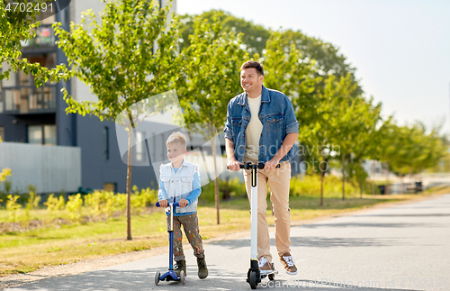 Image of father and little son riding scooters in city