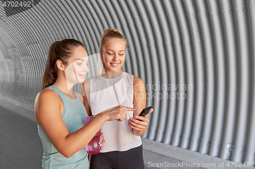 Image of women or female friends with smartphone and flask