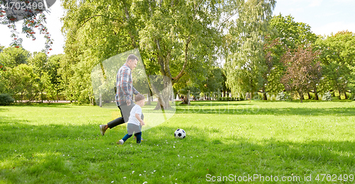 Image of happy father and son playing soccer at summer park