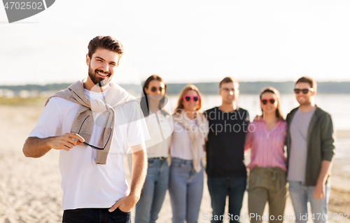 Image of happy man with friends on beach in summer