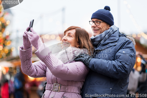 Image of senior couple taking selfie at christmas market