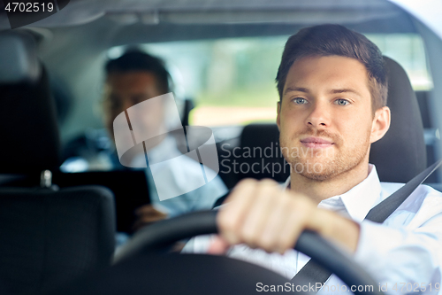 Image of male taxi driver driving car with passenger