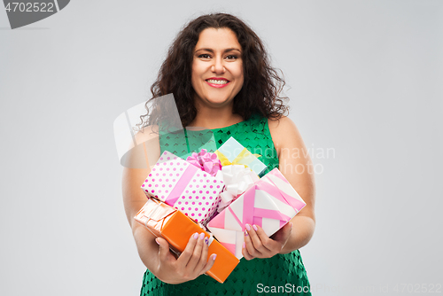 Image of happy woman in green dress holding gift boxes