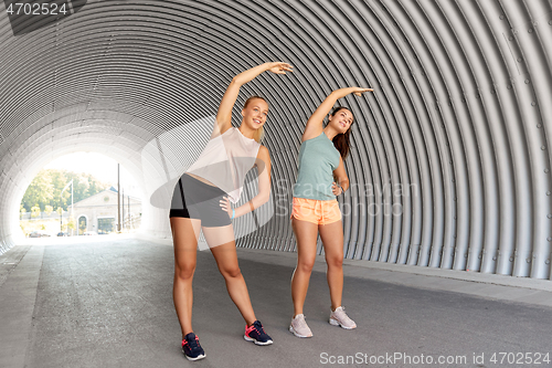 Image of women with fitness trackers stretching outdoors