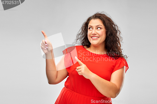 Image of happy woman in red pointing fingers at something