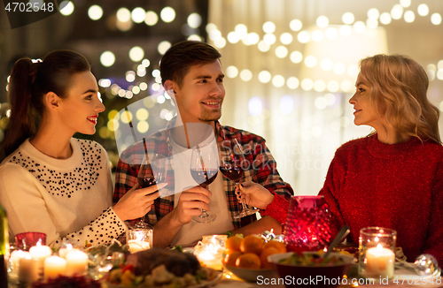 Image of happy friends drinking red wine at christmas party