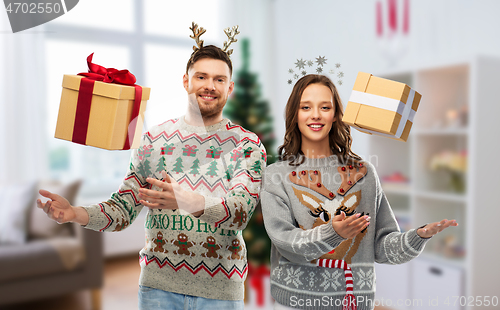 Image of happy couple in christmas sweaters with gift boxes