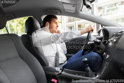 Image of man or driver with wireless earphones driving car