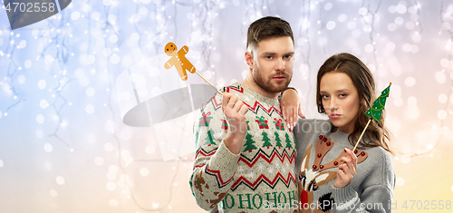 Image of couple with christmas party props in ugly sweaters