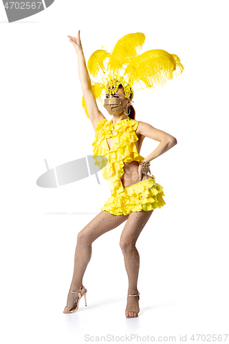 Image of Beautiful young woman in carnival, stylish masquerade costume with feathers dancing on white studio background.