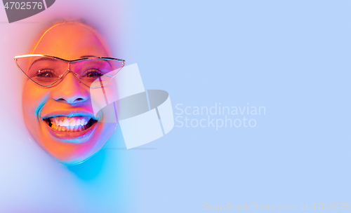 Image of Beautiful female face in the milk bath with soft glowing in blue-pink neon light