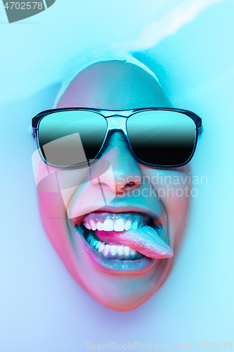 Image of Beautiful female face in the milk bath with soft glowing in blue-pink neon light