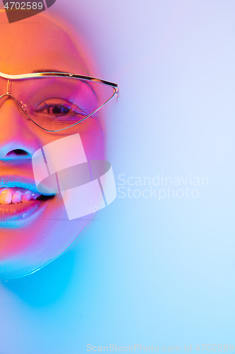 Image of Beautiful female face in the milk bath with soft glowing in blue-pink neon light