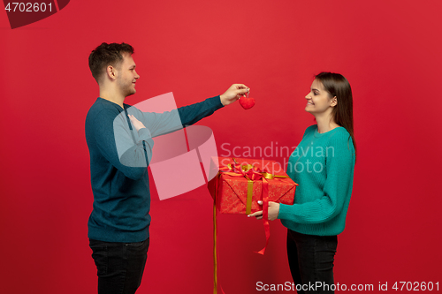 Image of Beautiful couple in love on red studio background. Valentine\'s Day, love and emotions concept