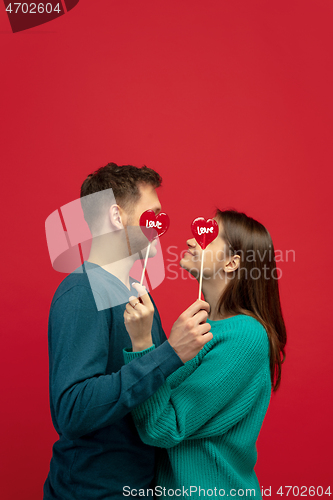 Image of Beautiful couple in love on red studio background. Valentine\'s Day, love and emotions concept