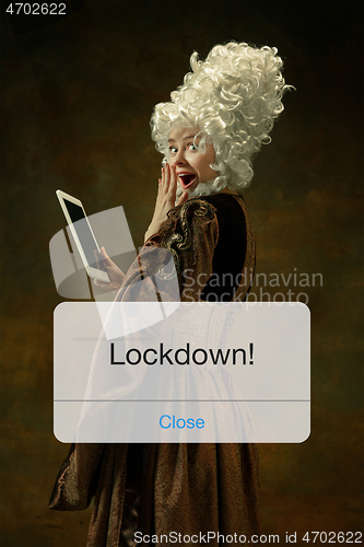 Image of Medieval young woman in old-fashioned costume with tablet behing the message with word Lockdown