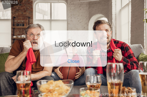 Image of Excited, shocked soccer fans cheering for favourite sport team in restaurant or home behind the message with word Lockdown