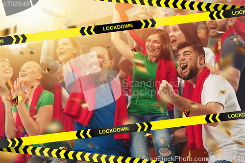 Image of Female and male soccer fans cheering for favourite sport team with bright emotions, excited, wondered behind the limiting tapes with Lockdown