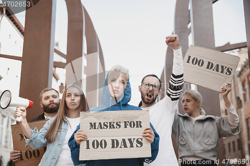 Image of Group of activists protesting, supporting masks for 100 days in America. Look angry, hopeful, confident. Banners and smoke. Coronavirus.