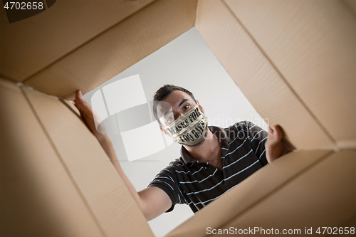 Image of Young man in face mask with sign masks for 100 days in USA opening the biggest postal package