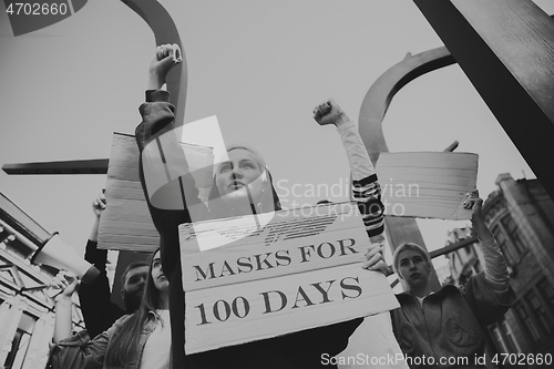 Image of Group of activists protesting, supporting masks for 100 days in America. Look angry, hopeful, confident. Banners and smoke. Coronavirus.