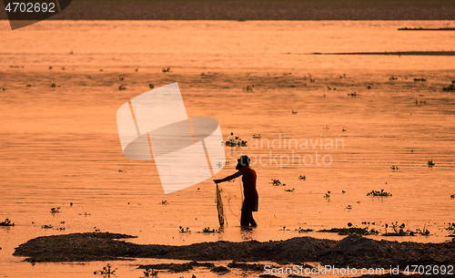 Image of Asian Woman fishing in the river, silhouette at sunset