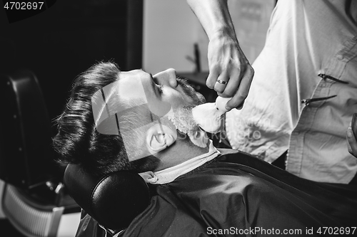 Image of Client during beard shaving at barbershop.