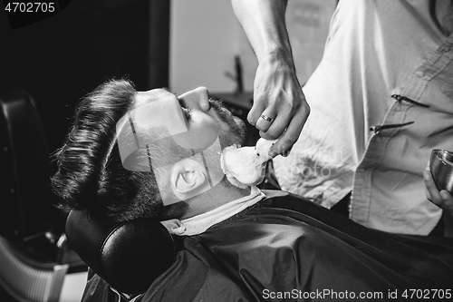 Image of Client during beard shaving at barbershop.