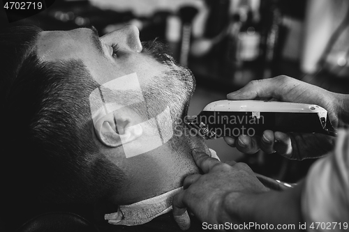 Image of Client during beard shaving at barbershop.