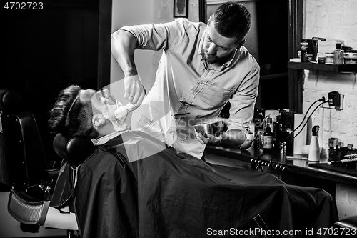 Image of Client during beard shaving at barbershop.