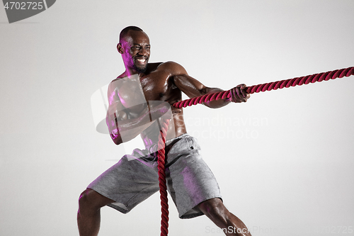 Image of Young african-american bodybuilder training over grey background