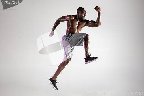 Image of Young african-american bodybuilder training over grey background