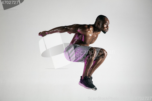 Image of Young african-american bodybuilder training over grey background