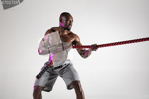 Image of Young african-american bodybuilder training over grey background