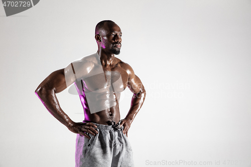 Image of Young african-american bodybuilder training over grey background