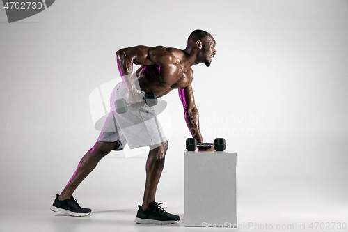 Image of Young african-american bodybuilder training over grey background