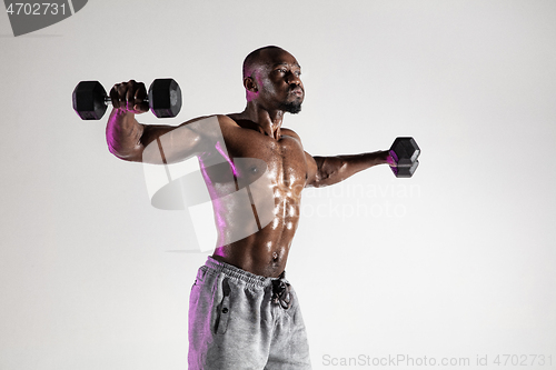 Image of Young african-american bodybuilder training over grey background