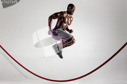 Image of Young african-american bodybuilder training over grey background