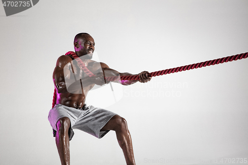 Image of Young african-american bodybuilder training over grey background