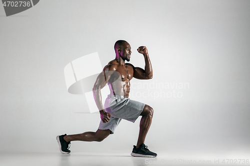 Image of Young african-american bodybuilder training over grey background