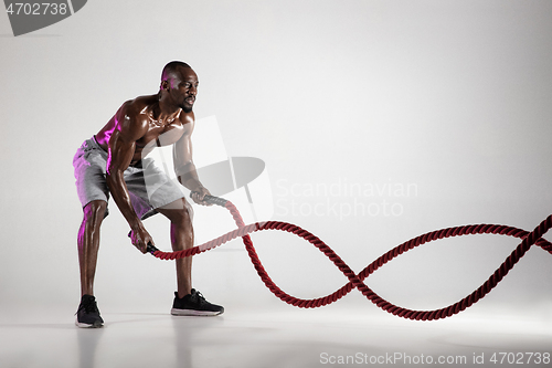 Image of Young african-american bodybuilder training over grey background