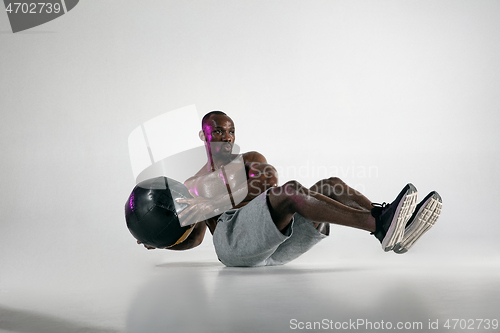 Image of Young african-american bodybuilder training over grey background