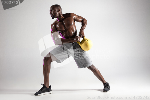 Image of Young african-american bodybuilder training over grey background