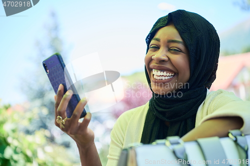 Image of african woman using smartphone wearing traditional islamic clothes